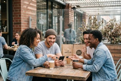 Groupe de jeunes souriants discutant en terrasse urbaine