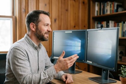 Homme utilisant une interface de prise en main à distance sur un double écran depuis son bureau à domicile, comme lors d'un appel vidéo naturel